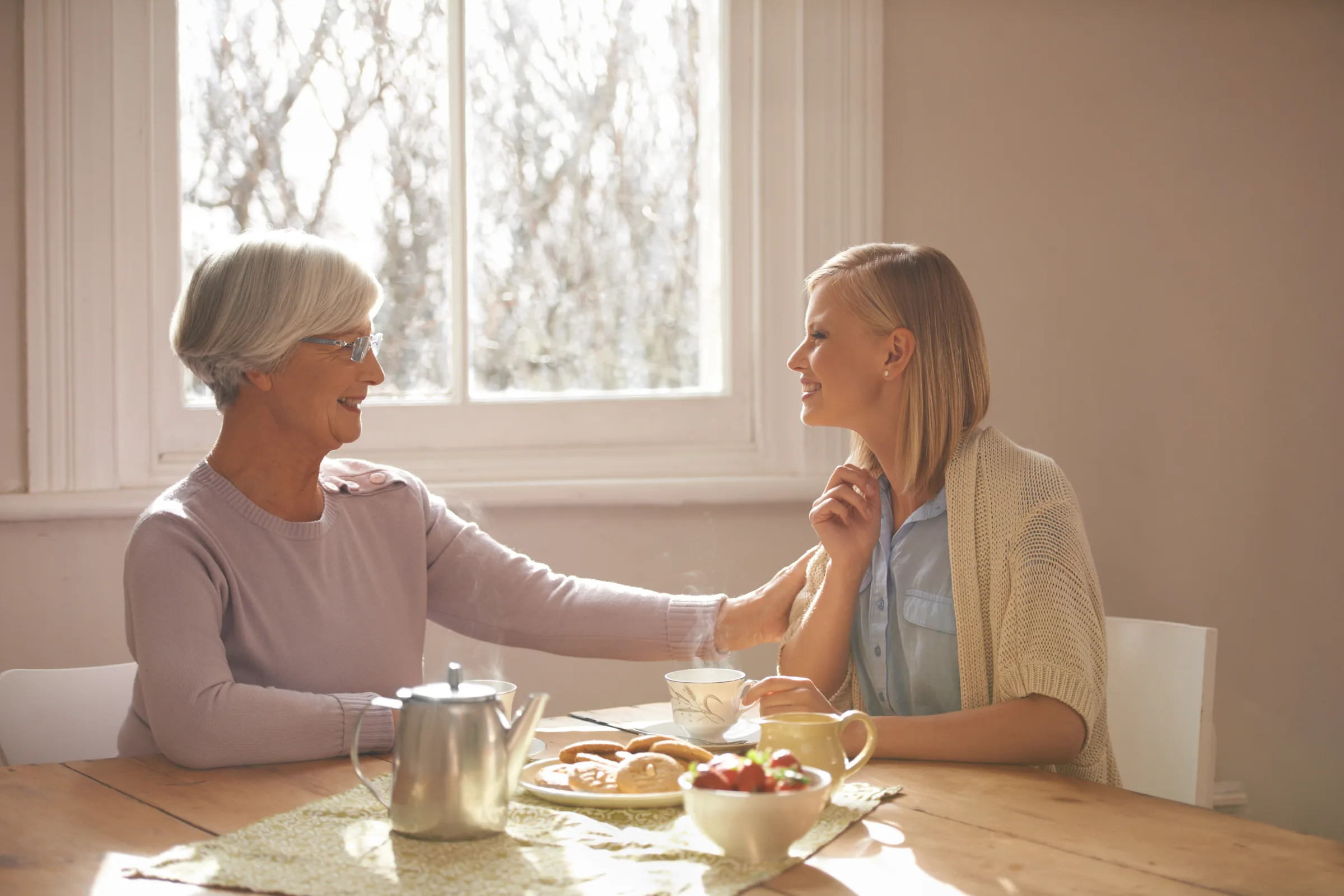 A grandmother sharing tea with two family members at the kitchen table
